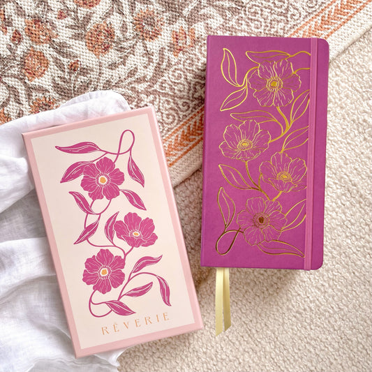 Reverie Traveler Size Journal in a magenta color, with gold foil floral design on cover. With watercolor dotted paper