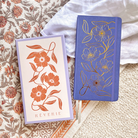 Reverie Traveler Size Journal in a periwinkle blue color with gold foil floral design on cover. With watercolor dotted paper