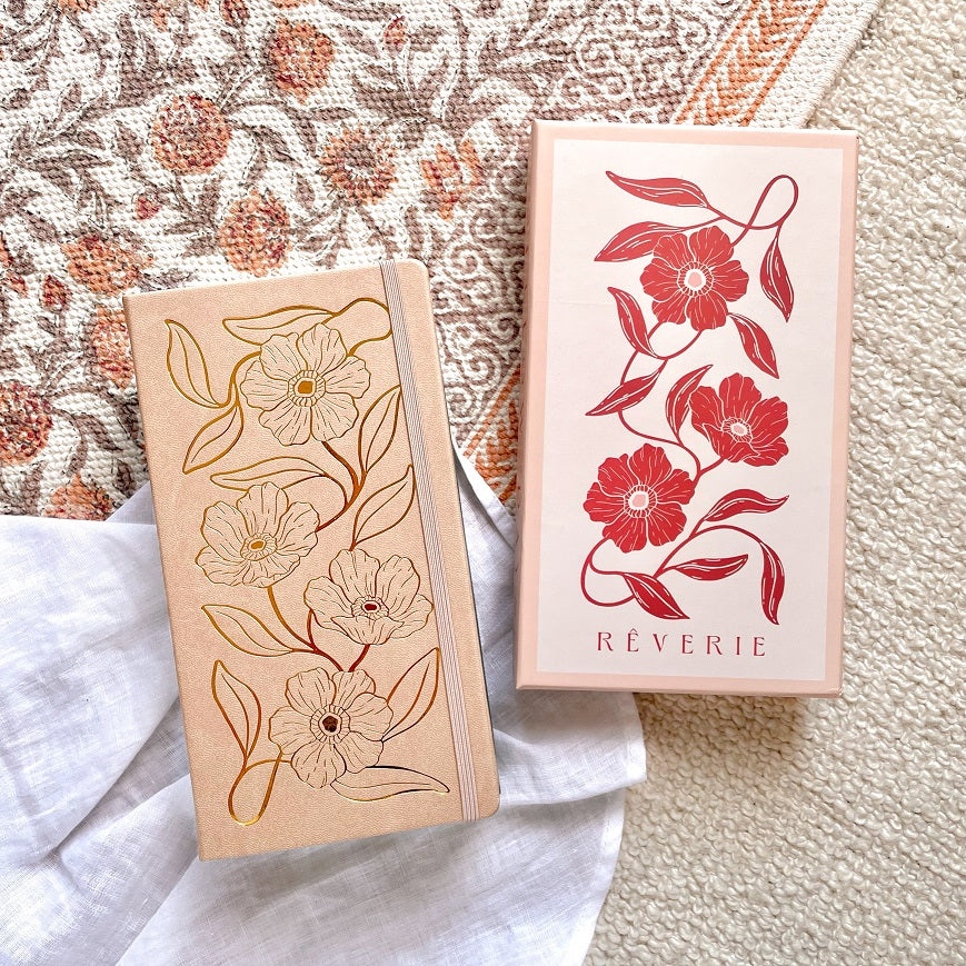 Reverie Traveler Size Journal in a light beige color with gold foil floral design on cover. With watercolor dotted paper