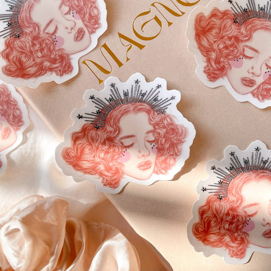    la reveuse vinyl sticker is 76 mm by 62 mm, illustrated with a pretty girls face with short curly hair and a star trimmed crown
